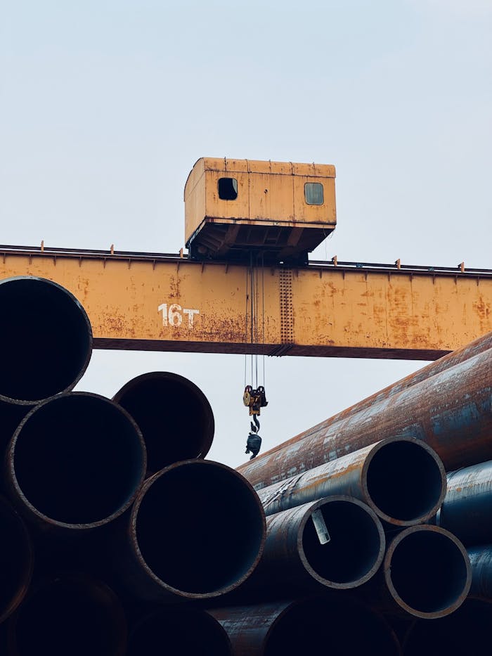 An industrial crane operates over stacked steel pipes at Tianjin Port, China.